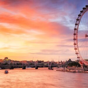 The illuminated London Eye reflects over the River Thames at the sunset, showcasing vibrant city lights.
