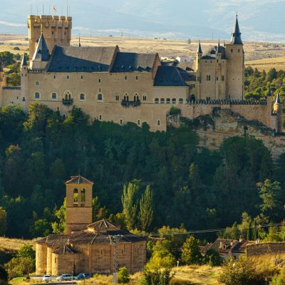 Alcázar Segovia Stunning view of the Alcázar of Segovia surrounded by autumn foliage.