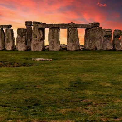 Capture of the iconic Stonehenge during a vibrant sunset with a dramatic sky.